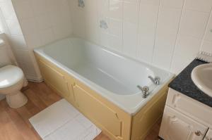 a bathroom with a tub and a toilet and a sink at Strathallan Guest House in Helston