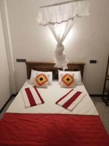 a bed with two red and white pillows on it at Flip Flop Inn Mirissa in Mirissa