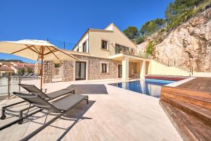 a villa with a swimming pool and two chairs and an umbrella at Villa Diamond by Cap Vermell Estate in Canyamel