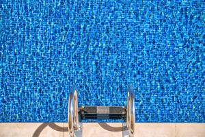 - une piscine avec une chaise en face d'une piscine bleue dans l'établissement Villa Diamond by Cap Vermell Estate, à Canyamel
