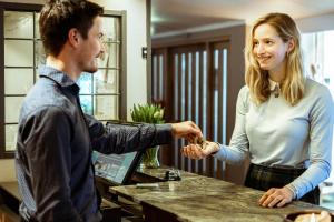 a man and a woman shaking hands at a counter at Venabu Fjellhotell in Venabygd