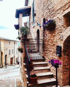 un edificio de piedra con escaleras y flores. en Domus Flora Guest House, en Spello
