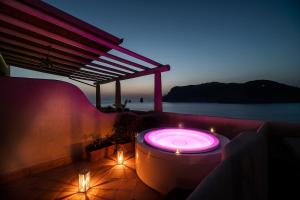 bañera de hidromasaje con luces en el patio por la noche en Therasia Resort Sea and SPA - The Leading Hotels of the World en Vulcano