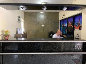 un hombre sentado en un mostrador en una habitación en CP Hotel Economic, en Natal