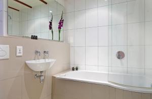 ein Badezimmer mit einer Badewanne, einem Waschbecken und einem Spiegel in der Unterkunft Lalapanzi Lodge in Somerset West
