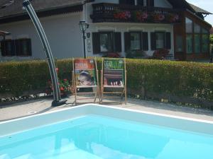 two chairs in front of a house with a swimming pool at Ferienhaus Rustica in Rohrbach am Kulm