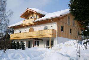 una casa con nieve delante en Heidi's Ferienwohnung2 en Dietramszell