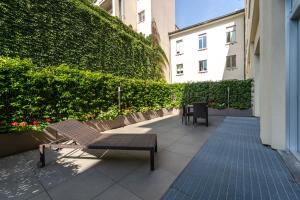 eine Terrasse mit zwei Bänken und einer grünen Hecke in der Unterkunft Hotel Milano Castello in Mailand