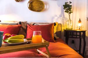 a table with a plate of fruit and a glass of orange juice at Camões Lofty Boho Apartment in Setúbal