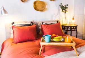 a tray of fruit on a bed with red pillows at Camões Lofty Boho Apartment in Setúbal +21 photos