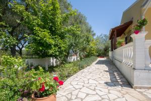 
a small house with a flower garden in front of it at Karia Holiday Home in Lefkimmi
