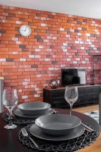 a table with two glasses and a clock on a brick wall at Apartament Dla Ciebie in Olsztyn