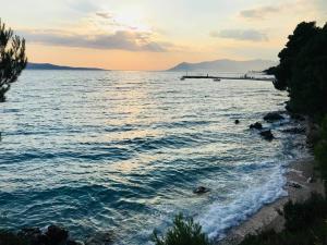 a beach with a pier in the water at sunset at Apartments Ruzica in Makarska