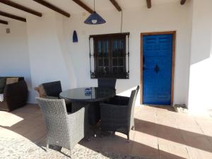 eine Terrasse mit einem Tisch, Stühlen und einer blauen Tür in der Unterkunft Casa del Limonero in Guaro
