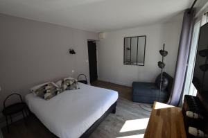 a bedroom with a white bed and a blue chair at Hotel De Quebec in Rouen