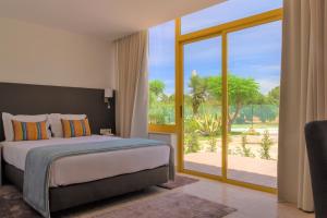 um quarto com uma cama e uma porta de vidro deslizante em Hotel Pinhal do Sol em Quarteira