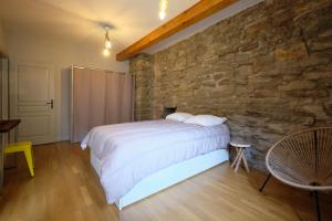 een slaapkamer met een bed en een stenen muur bij Mélina - appartement dans les remparts de la Bastide avec parking et terrasse in Carcassonne