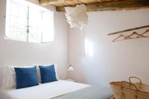 sypialnia z łóżkiem z niebieskimi poduszkami i oknem w obiekcie Casas de Mértola 29 w mieście Mértola