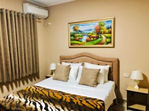 a bed in a hotel room with a painting on the wall at Tirana Central Apartment - Spacious 2 Bedroom in Tirana
