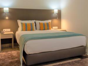 Hotel Pinhal do Sol في كوارتيرا: غرفة نوم بسرير كبير مع وسادتين