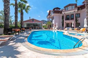 a swimming pool in front of a house with palm trees at Minta Apartments in Dalyan