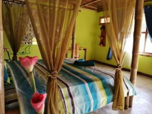 um quarto com uma cama com cortinas e flores em Hotel Rio Celeste Finca L´ Etoile Celeste em El Achiote