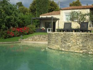 una casa con una pared de piedra junto a una piscina en Gîte du Jardin des Espuys, en Venasque