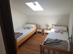 a small room with two beds and a skylight at Apartman Ravlić in Malinska