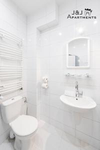 a white bathroom with a toilet and a sink at J&J Apartments Łazienna 30 Apartament 10-5 in Toruń