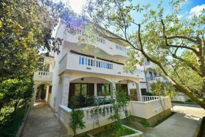 a white house with trees in front of it at Apartments Mrva in Ugljan