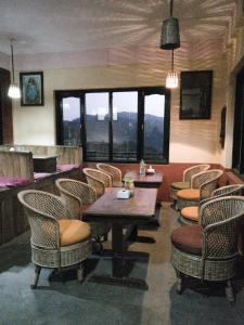 ein Restaurant mit einem Tisch, Stühlen und Fenstern in der Unterkunft Berg House Cafe and Hotel in Nagarkot
