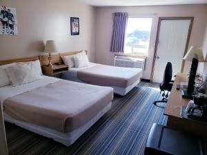 a hotel room with two beds and a desk at Travel-Inn Resort & Campground in Saskatoon