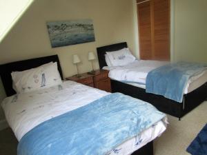 two beds in a room with a blue wall at The Old Post House in Moretonhampstead