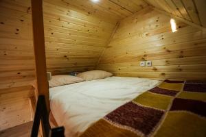 Bett in einem Holzzimmer mit einer Holzwand in der Unterkunft BUKHRIANI in Kutaissi