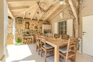 a dining room with a wooden table and chairs at White Cottage Heritage House in Čižići