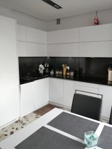 a kitchen with white cabinets and a table and chairs at Apartament Kopernik in Wadowice