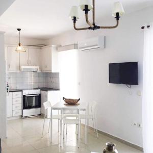 a kitchen with a table and chairs and a tv at AQUALIA Apartment 1 in Karpathos