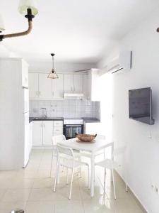 a white kitchen with a white table and chairs at AQUALIA Apartment 1 in Karpathos