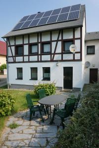 a table and chairs in front of a house with solar panels at Ferienwohnung Czornebohblick in Kubschütz