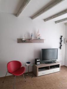 a living room with a television and a red chair at Gaviota in Caleta De Fuste