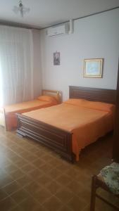 2 Betten in einem Schlafzimmer mit orangefarbener Bettwäsche in der Unterkunft B e B Il Vigneto in Petacciato