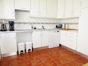 a white kitchen with white cabinets and a tile floor at IM On Luz Arte in Luz
