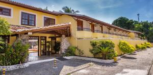 a yellow house with a courtyard in front of it at Chauã Porto Hotel in Porto Seguro