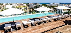 a swimming pool with chairs and umbrellas on a building at Serenity Hotel Boutique By Alsol in Playa del Carmen