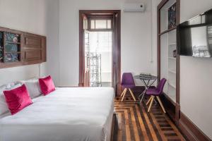 a bedroom with a bed and two purple chairs at Urban Suites in Aveiro