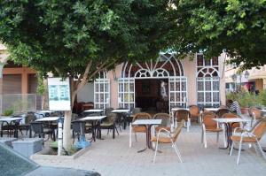 un patio vuoto con tavoli e sedie sotto un albero di Hotel Atlas Ouarzazate a Ouarzazate