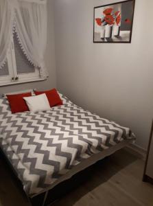 a bed with black and white sheets and red pillows at Apartament dla Ciebie in Sztutowo
