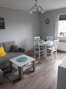 ein Wohnzimmer mit einem Sofa, einem Tisch und Stühlen in der Unterkunft Apartament dla Ciebie in Sztutowo