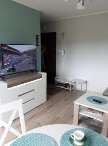 ein Wohnzimmer mit einem TV und einem Tisch in der Unterkunft Apartament dla Ciebie in Sztutowo