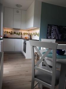 a kitchen with white cabinets and a table and a chair at Apartament dla Ciebie in Sztutowo